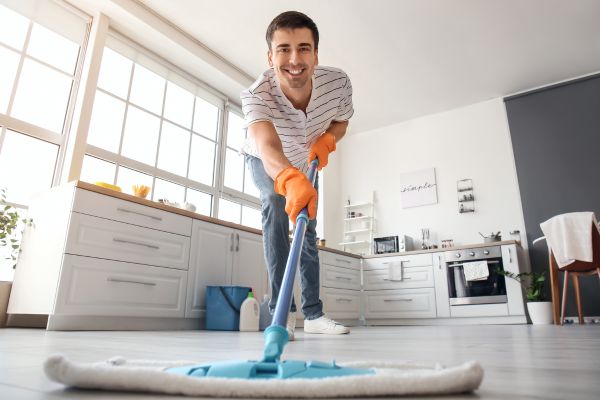 Bild zeigt einen Mann, der in einer Wohnung den Boden wischt.